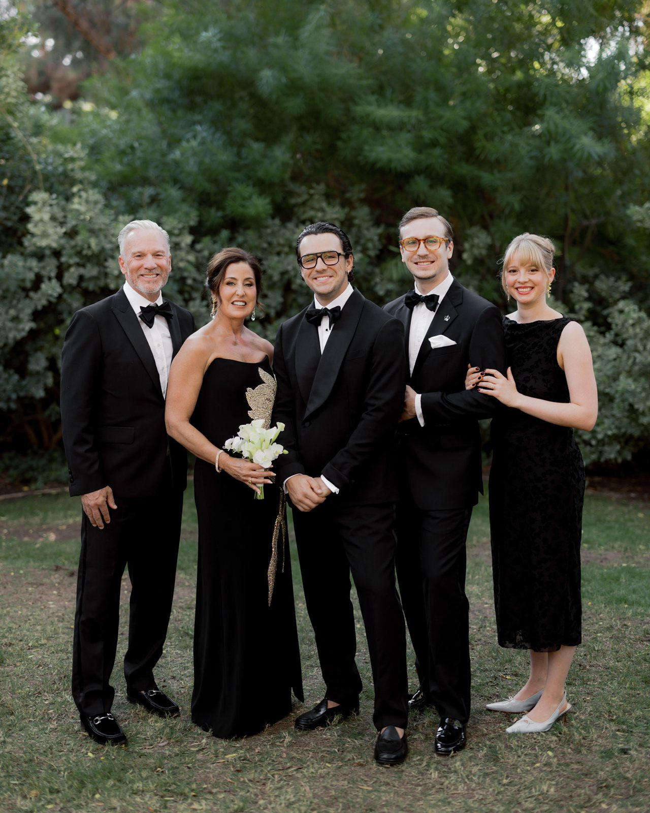 Glenn and Liz Fisher with their sons and daughter-in-law in black tie, garden setting